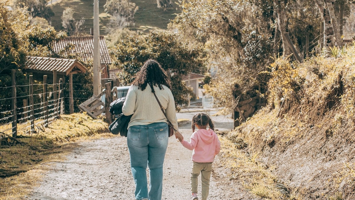 a woman and child walking down a dirt road